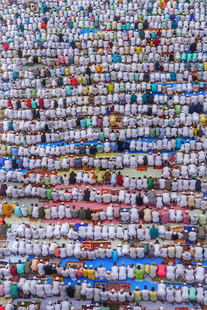 Top view of a large gathering in traditional clothing engaged in prayer.